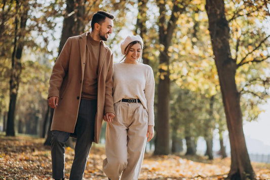 Paar in minimalistischen Outfits in neutralen Farben spaziert durch einen herbstlichen Park – Guide zu Herbst Outfits 2025