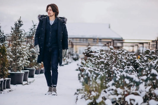 Mann geht durch den Schnee mit winterlichem Outfit und dunkler Hose; Beispiel für warme, klare Winterlooks.